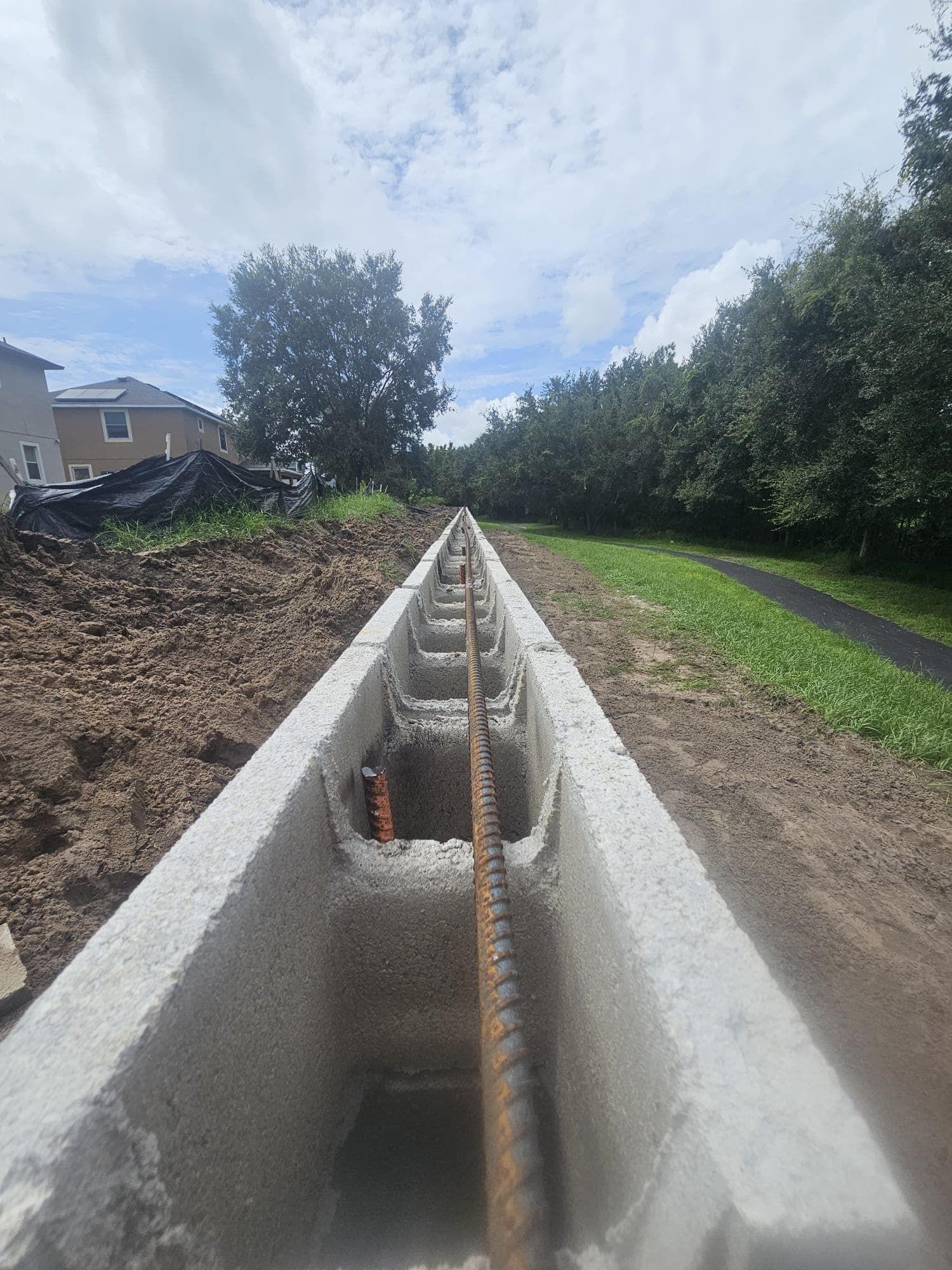 Long row of hollow concrete blocks with a rusty rebar rod running through the center.