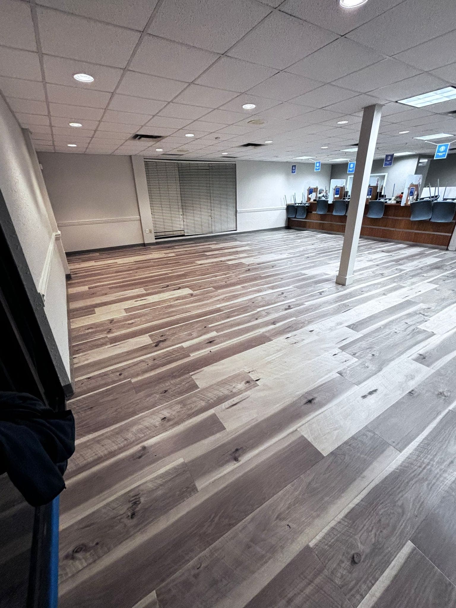 Empty customer service area featuring multi-toned wood floors, a long counter, and a white pillar.