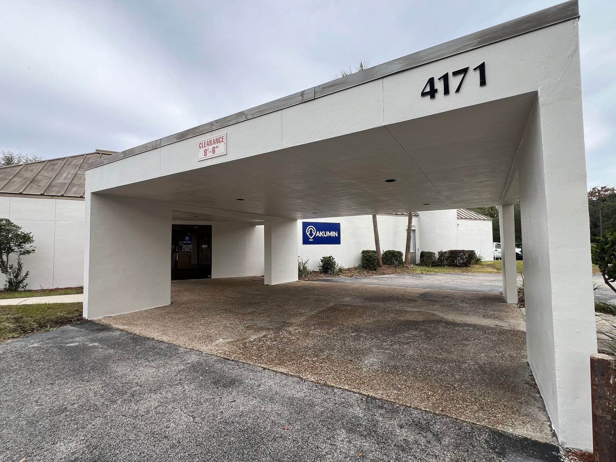 White covered entrance for building 4171 with an Akumin sign and 8'-6" clearance marker.